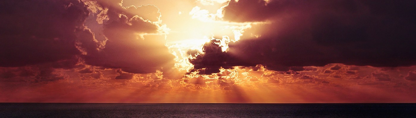 sun shining through clouds over water